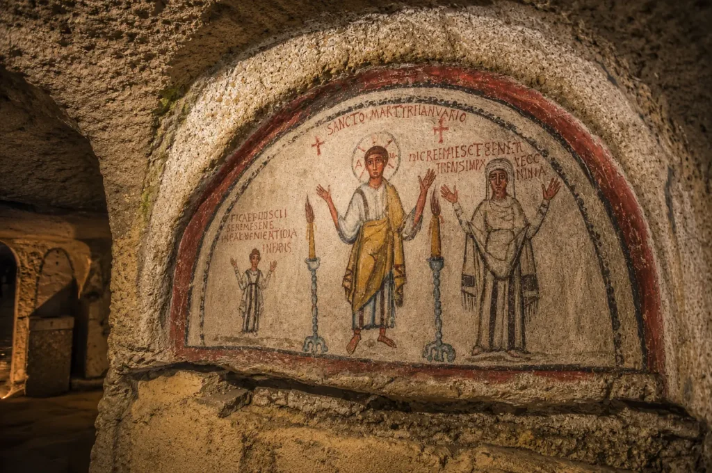 Ancient Christian fresco inside the Catacombs of San Gennaro in Naples featuring early religious artwork and underground stone architecture.