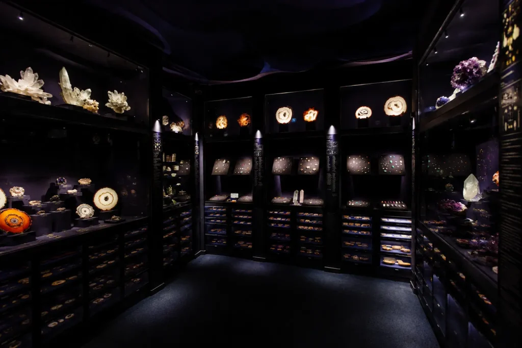 Dark mineralogy gallery inside La Specola Museum in Florence featuring glowing gemstones, crystals, and geological exhibits