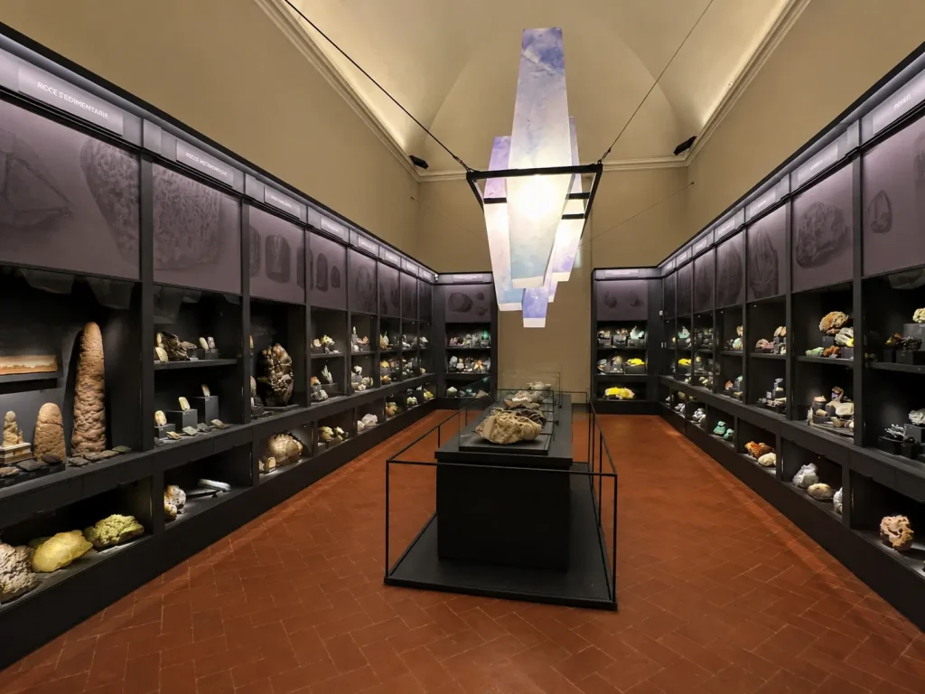 The mineralogy hall inside La Specola Museum in Florence featuring gemstones, crystals, and illuminated geological exhibits