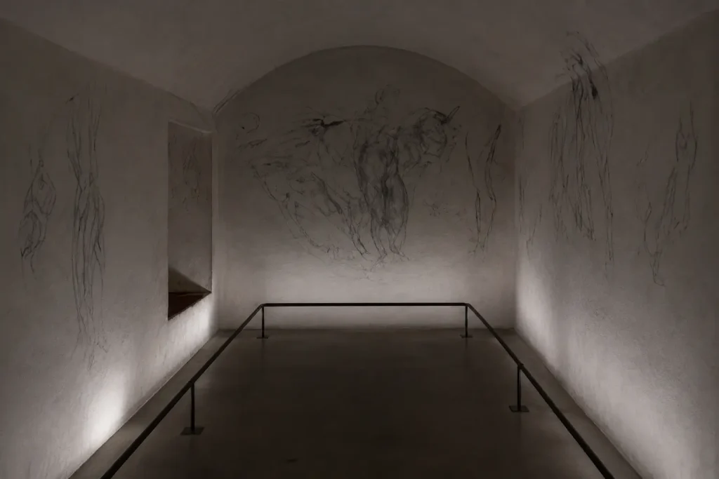 Dimly lit interior of Michelangelo’s Secret Room beneath the Medici Chapels in Florence with charcoal sketches covering the walls