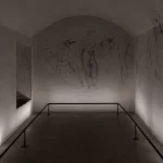 Dimly lit interior of Michelangelo’s Secret Room beneath the Medici Chapels in Florence with charcoal sketches covering the walls