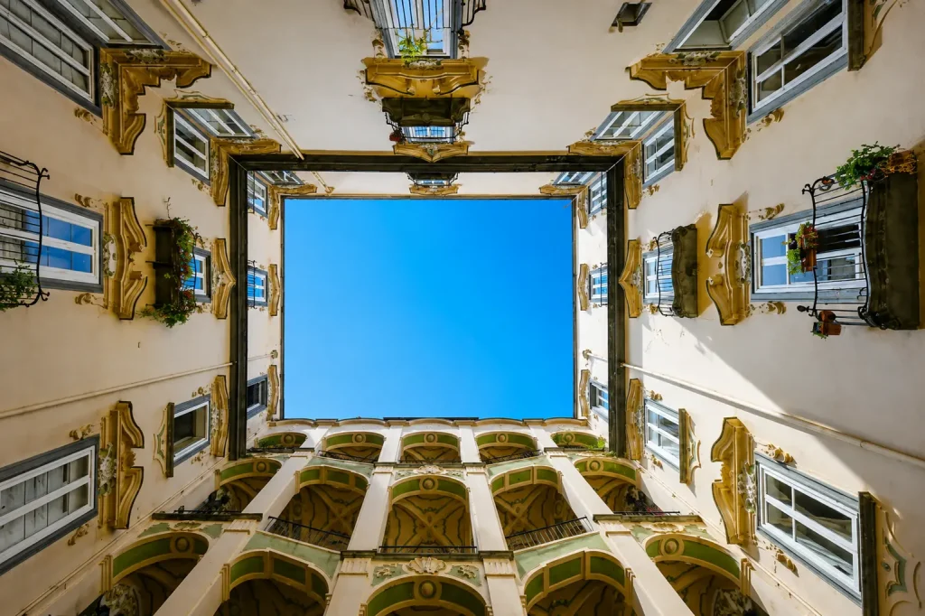 Looking up at the courtyard and bright blue sky inside Palazzo dello Spagnolo in Naples, Italy