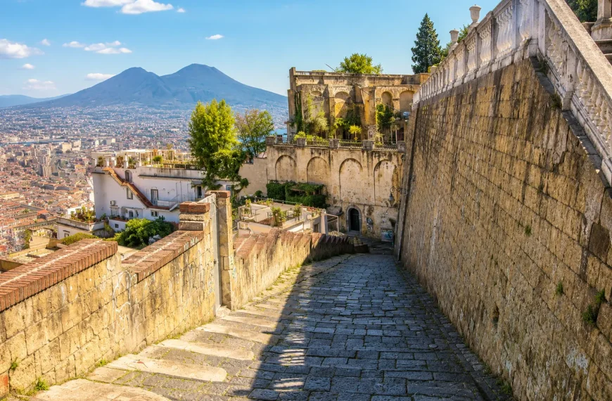 Historic stone staircase of Pedamentina a San Martino in Naples with panoramic city views and Mount Vesuvius under a sunny blue sky.