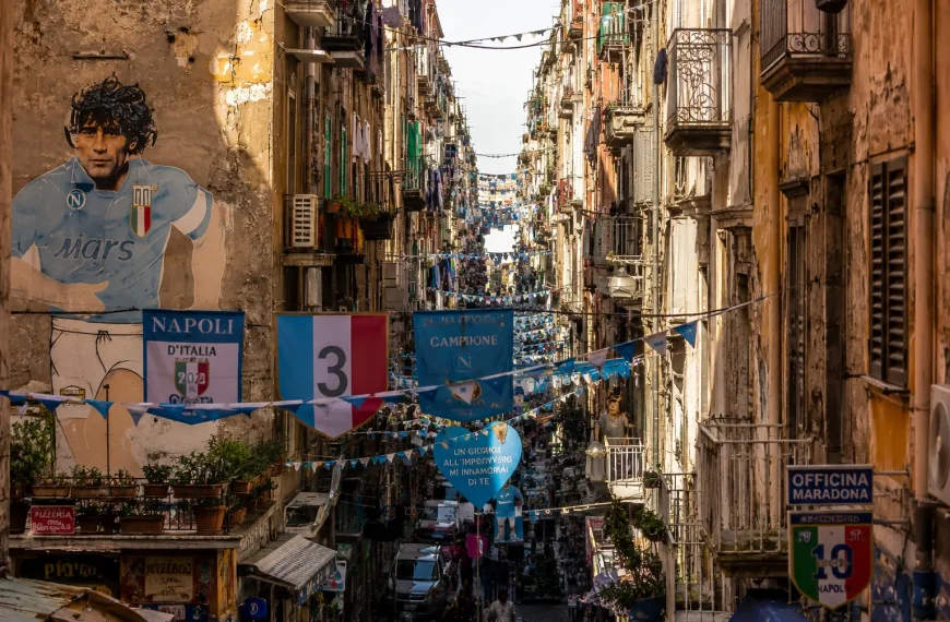 Narrow street in Quartieri Spagnoli, Naples, featuring colorful buildings, Maradona murals, hanging laundry, and authentic Neapolitan street life.
