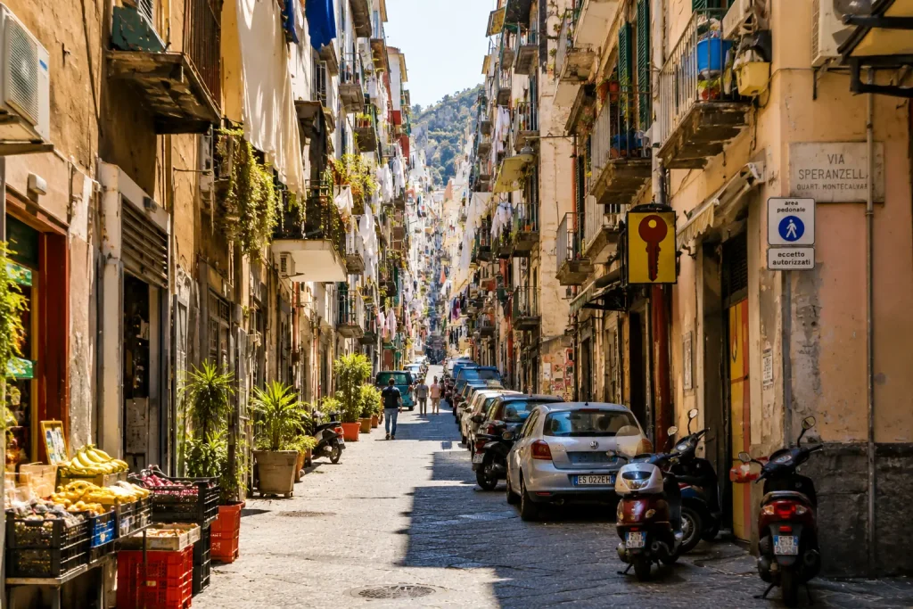 Sunny narrow street in Quartieri Spagnoli Naples with hanging laundry, scooters, balconies, and traditional buildings