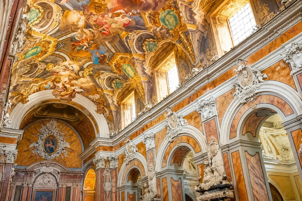 Magnificent Baroque interior of Santa Chiara in Naples featuring ornate frescoed ceilings, marble architecture, gilded decorations, and richly decorated arches illuminated by natural light.