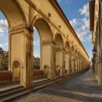 The Vasari Corridor in Florence with long Renaissance arches and an empty historic walkway above the Arno River