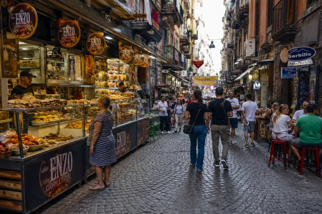 Busy food street in Vico Lungo Gelso Naples with local eateries, tourists, street food, and traditional buildings in Quartieri Spagnoli
