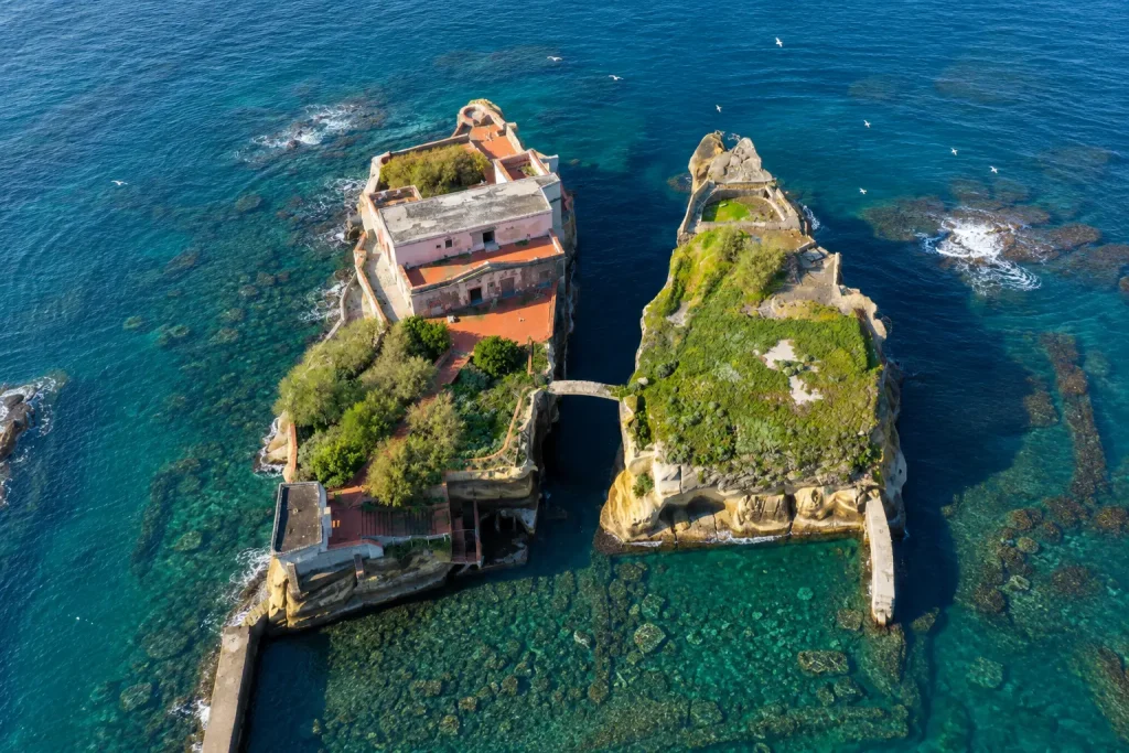 Aerial view of La Gaiola Island in Naples showing the twin islets, connecting bridge, crystal-clear water, and submerged Roman ruins