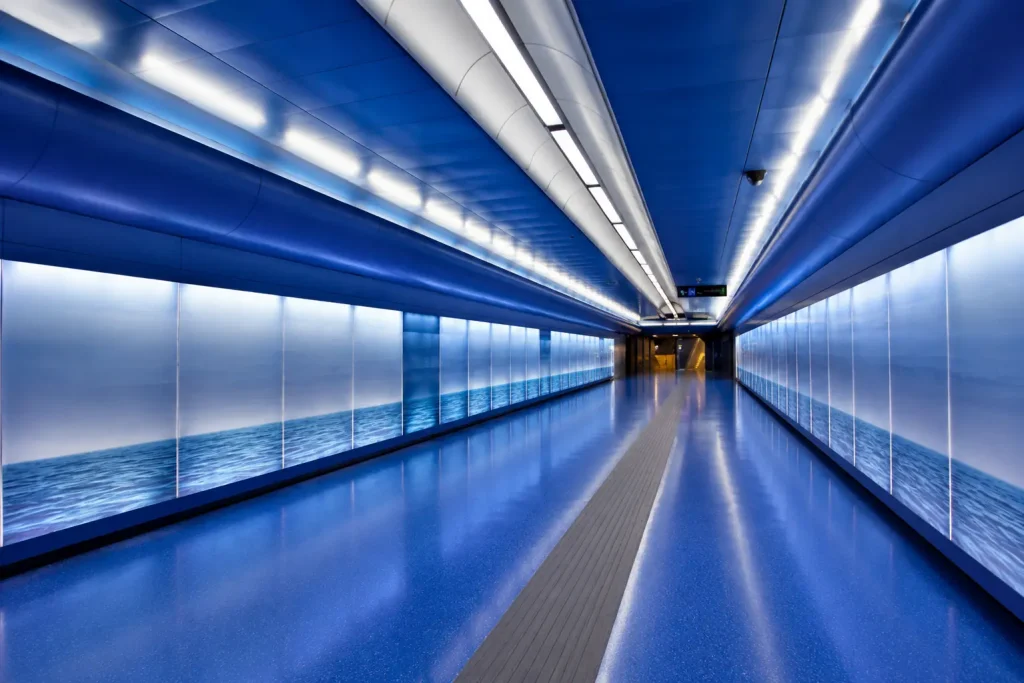 Blue illuminated corridor inside Toledo Metro Station in Naples, featuring futuristic architecture, ocean-inspired design, and the famous Art Stations project.
