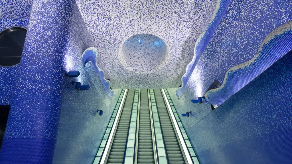 Blue mosaic escalators inside Toledo Metro Station in Naples, showcasing the station's underwater-inspired design and award-winning contemporary architecture.